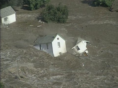 White wooden house in heavy flood water floating away, USA - Wazee Digital